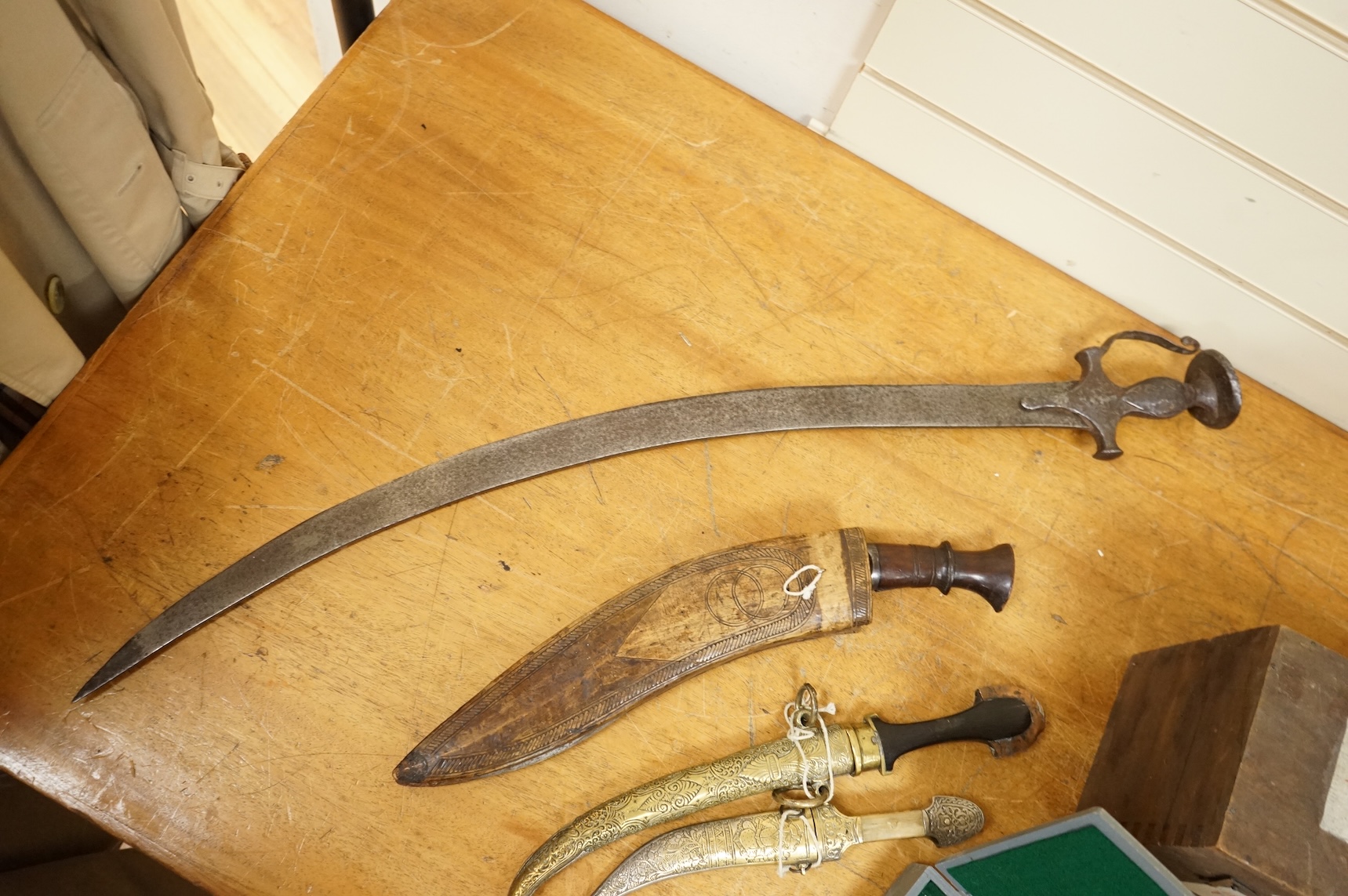 An Indian sword tulwar, the iron hilt with traces of chiselled and inlaid decoration, together with a kukri in its wooden scabbard, a Syrian jambya and a Moroccan jambiya (4)